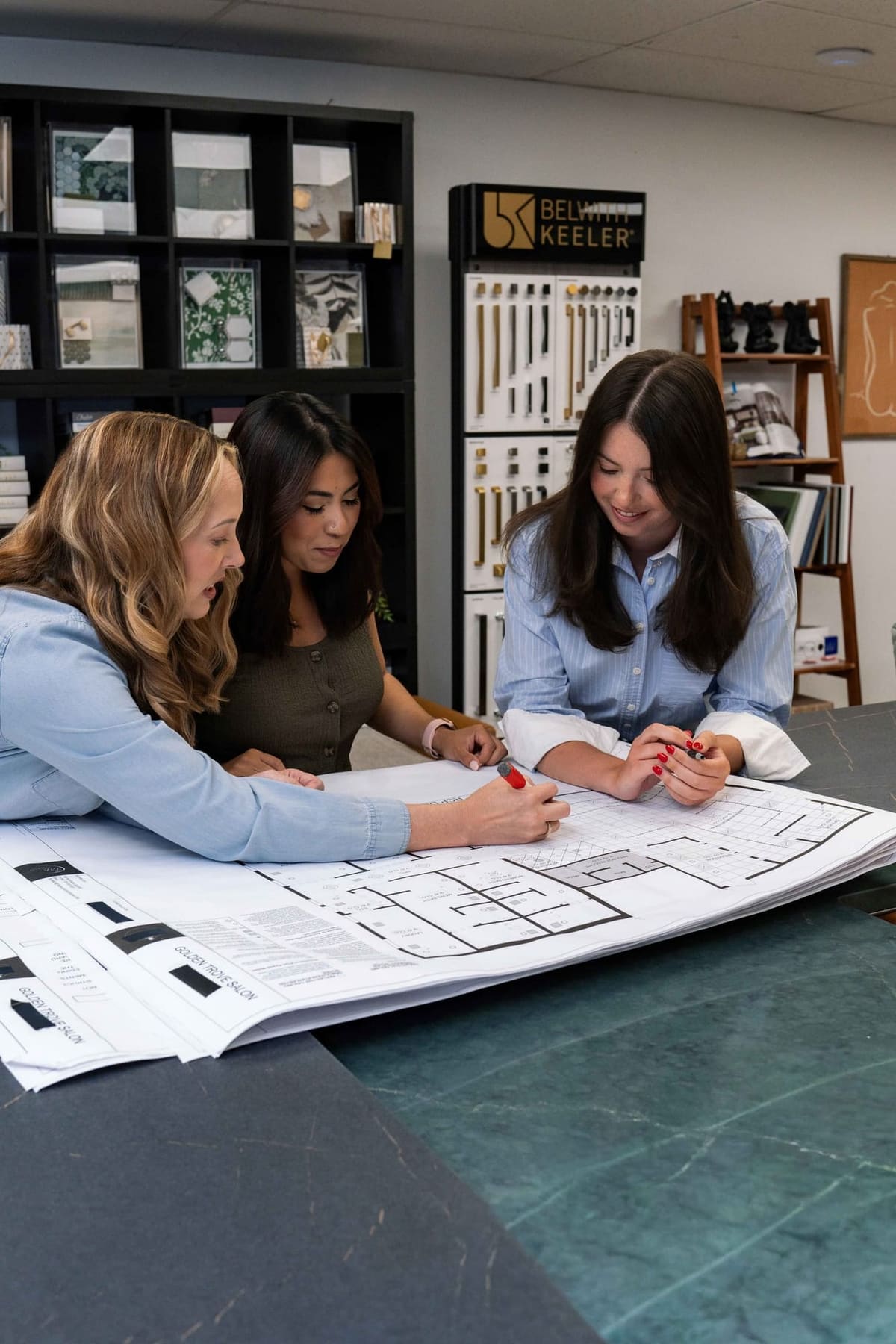 Trish Bonney marking up a floor plan with Maira Santos and Gabby Hinchey at the TAB showroom table